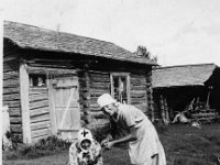Leuhulan Heta Stiina tyttarensa Siirin kanssa  Heta-Stiina Leuhula  istuu Leuhulan pihassa perunoita kuorimassa edessään kaksi puuastiaa. Vierellä seisoo hänen tyttärensä Siiri Tähtinen (myöhemmin Mäki). Takana kaksi rakennusta, oikealla etualalla ruukkukasvi.
